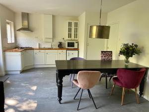 una cocina con mesa negra y sillas moradas en Natuurpark Hoefbos Boshuisje Veluwe, en Otterlo