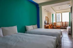 two beds in a room with a green wall at Hermit Crab B&B in Wuqi