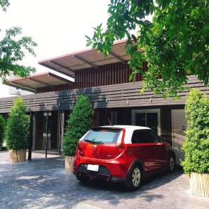 a red car parked in front of a building at Lamoon Boutique Hotel in Suphan Buri