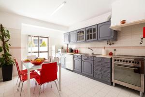 une cuisine avec des armoires bleues et une table avec des chaises rouges dans l'établissement Ericeira Central Apartment, à Ericeira
