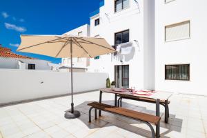 une terrasse avec une table, un parasol et un banc dans l'établissement Ericeira Central Apartment, à Ericeira