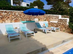 a group of chairs and an umbrella next to a wall at San Colomban in Sant Lluis