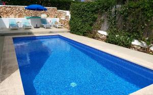 niebieski basen z krzesłami i parasolem w obiekcie San Colomban w mieście Sant Lluis