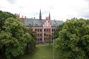 a large red brick building with a tower at Cozy Home Valdemara, free parking, self check-in in Rīga