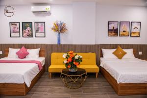 a hotel room with two beds and a vase of flowers at Sơn Hà Hotel in Quy Nhon +15 photos