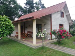 een klein wit huis met een tafel en bloemen bij Chatka pod Dębami in Brzeźnica