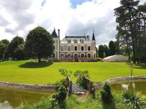 Saint-Paul-en-Jarez的住宿－Eclosion Château Hôtel & Restaurant，一座白色的大房子,前面有一个池塘