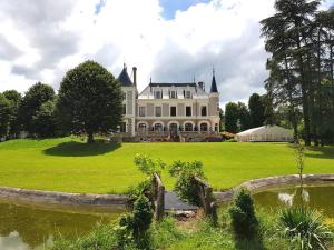 uma grande casa branca com um lago em frente em Eclosion Château Hôtel & Restaurant em Saint-Paul-en-Jarez