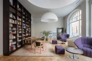 a library with purple chairs and tables and bookshelves at Neiburgs Hotel in Riga
