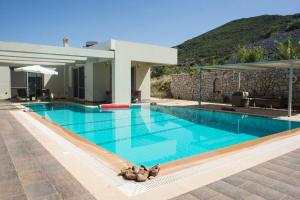 a swimming pool with a villa with a mountain in the background at Modern Luxury Villa with Pool, just 5min to sea in Kalamata