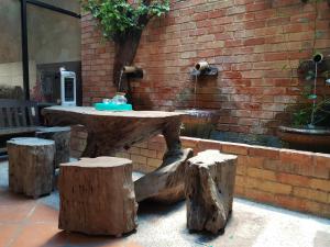 a wooden table with logs around it next to a brick wall at 5imply 9ice Heritage in George Town