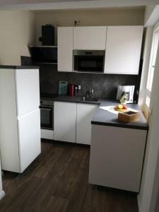 cocina con armarios blancos y encimera negra en Ferienwohnung - Nadine en Georgsmarienhütte