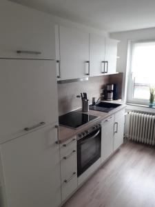 a kitchen with white cabinets and a stove top oven at Möwennest in Neuharlingersiel