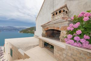 a stone fireplace with pink flowers on a balcony at Apartman Ružica in Pučišća