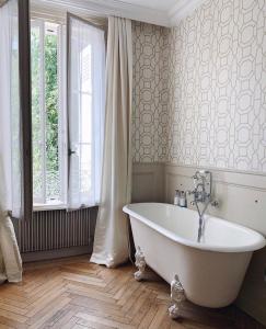 La salle de bains est pourvue d'une baignoire blanche et d'une fenêtre. dans l'établissement De la Chambre au Jardin, à Belleville-en-Beaujolais