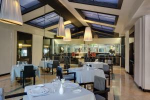ローマにあるグランド ホテル パレス ローマの白いテーブルと椅子、シャンデリアのあるレストラン