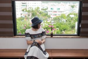 a woman sitting on a bench looking out a window at Sơn Hà Hotel in Quy Nhon