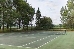 um campo de ténis com rede e algumas árvores em Great Higham Barn by Bloom Stays em Canterbury