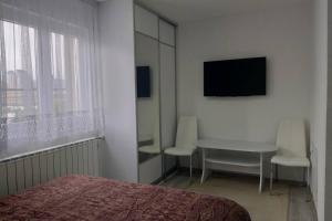 1 dormitorio con cama, mesa y TV en Vila E-N, en Sarajevo