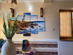a room with five paintings of the ocean and a lighthouse at Nemezis in Ustka