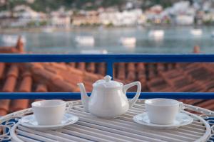 a table with two cups and a tea set on a balcony at Poros Home in Poros