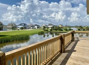 a wooden bridge over a river with houses at Dark Side Of The Dune home in Port Bolivar