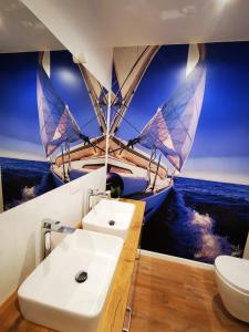 een badkamer met een wastafel en een zeilboot op het water bij M&K Apartamenty Deluxe Gdańsk Sobieszewo 2 in Gdańsk
