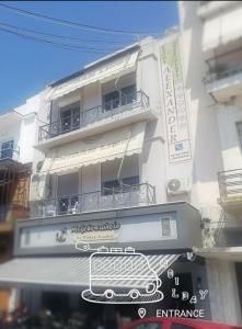 a white building with a sign in front of it at Alexander Rooms & Apartments in Igoumenitsa