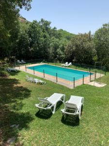 a swimming pool with two lawn chairs and a pool at Hotel Rural Porta Coeli - Dehesa Santa Lucía in San Martín del Castañar