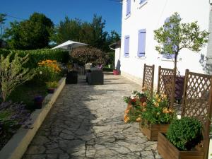 Una pasarela de piedra con flores en macetas junto a una casa en Hotel au Charme du Levat en Saint Paul de Loubressac