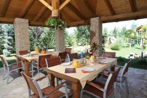 a patio with wooden tables and chairs under a pavilion at Airport Szálló in Tököl