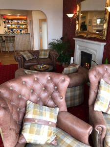 a living room with leather furniture and a fireplace at Queenswood Hotel in Weston-super-Mare