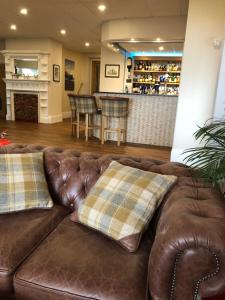 a brown leather couch with pillows in a living room at Queenswood Hotel in Weston-super-Mare
