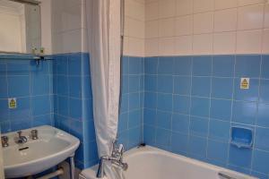 a blue tiled bathroom with a sink and a tub at The Orwell Hotel in Felixstowe