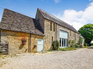 an old stone house with a driveway in front of it at Butts Farm in Cirencester