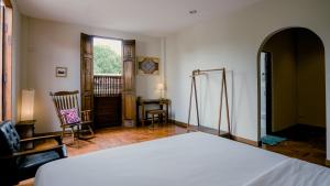 a bedroom with a white bed and a chair at Mammoth Art Studio Pool villa in old city in Chiang Mai