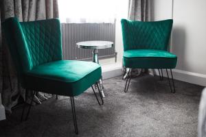 two green chairs and a table in a room at The Orwell Hotel in Felixstowe