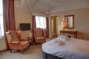 a hotel room with a bed and chairs and a television at The Orwell Hotel in Felixstowe