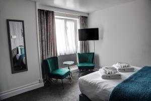a hotel room with a bed and two green chairs at The Orwell Hotel in Felixstowe