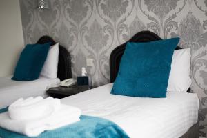 a hotel room with two beds with blue pillows at The Orwell Hotel in Felixstowe
