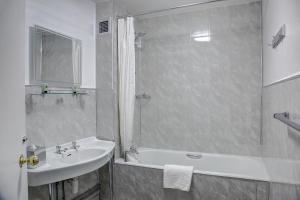 a white bathroom with a sink and a bath tub at The Orwell Hotel in Felixstowe
