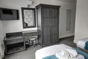 a bedroom with a cabinet and a desk and a bed at The Orwell Hotel in Felixstowe