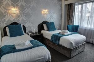 two beds in a hotel room with blue and white towels at The Orwell Hotel in Felixstowe