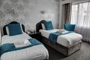 two beds in a hotel room with blue pillows at The Orwell Hotel in Felixstowe