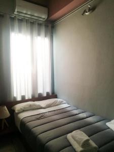 a bedroom with a bed and a window with a blanket at Alexander Rooms & Apartments in Igoumenitsa