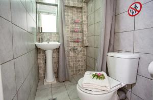 a bathroom with a white toilet and a sink at Ammos Studios & Apartments in Nea Peramos +18 photos