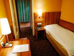 a hotel room with a bed and a desk with a desk at Rheinland Hotel in Bonn
