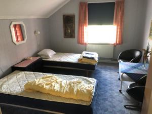 Zimmer mit 2 Betten, einem Stuhl und einem Fenster in der Unterkunft Älvtomt in Krylbo