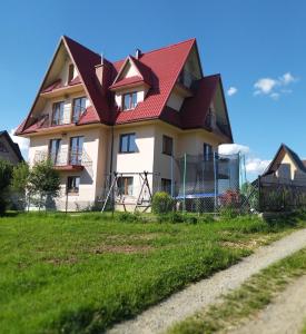 uma casa com um telhado vermelho no topo de um campo em U Marii & Mariana em Leśnica