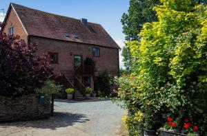 an old brick house with flowers in front of it at The Chaff House - farm stay apartment set within 135 acres in Bromyard